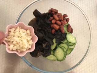 5、凉拌木耳黄瓜,将黄瓜片木耳和花生米倒入碗中然后倒入20g的蒜末
