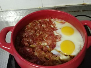 5、广式腊肠煲仔饭,当水分快要吸干，大米还略微冒泡的时候，可以把腊肠片放入，打两颗鸡蛋。继续小火焖8分钟。