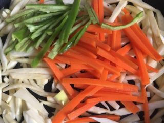 5、炒三丝,再加入红萝卜丝，辣椒丝一起炒，放盐，加一点清水，盖上盖子煮1分钟，上碟