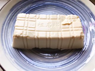 2、鲍鱼干贝XO酱拌香椿皮蛋豆腐,取出豆腐放入碗内，静置