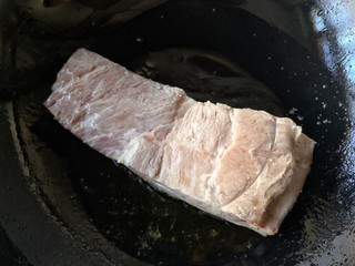 6、梅菜扣肉,锅中适量油烧热,将猪皮向下,入烧热的油锅里煎。