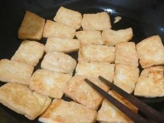 3、红烧豆腐,把豆腐一块一块放进油锅，一面煎黄后翻面，来回翻。把握时间，需要守着煎，直至金黄，呵呵