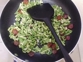 7、蒜苗炒腊肠,煎到腊肠透明就加入蒜苔，可以加点开水盖锅盖焖一会