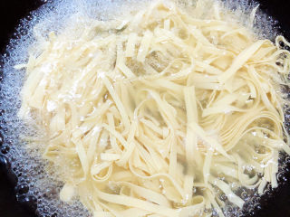 7、凉拌千张,锅中烧开水,烫一下豆腐丝,捞出淋水。