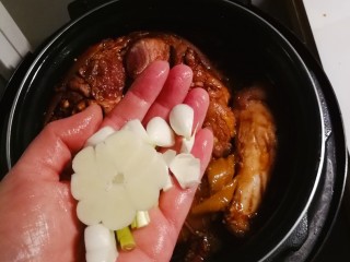 13、红烧肘子,放入蒜瓣、大葱。