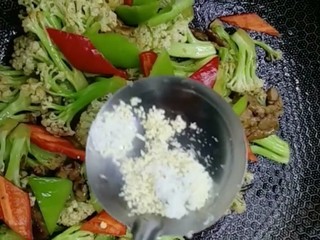8、干煸花菜,放入青红辣椒片，盐，鸡精，白糖调味，大火翻炒均匀出锅即可