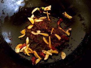 6、辣炒蛤蜊,放入姜丝、蒜瓣、葱白、花椒和干辣椒段稍炒一会。