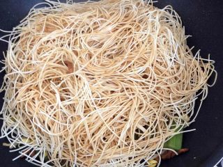 9、卤面条,把蒸过的挂面放入锅内,盖上锅盖大火烧五六分钟。掀开锅用筷子翻一下面条,这时候不要动底下的菜,然后把倒出来的半碗汤均匀的淋到面条上,再盖上锅盖中火烧几分钟。