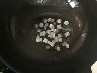 6、卤猪蹄,锅加热后放入植物油 ，后放入冰糖，翻炒。