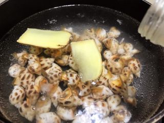 5、冰镇捞汁小海鲜,烧一锅水加入姜片和料酒，放入花螺焯熟