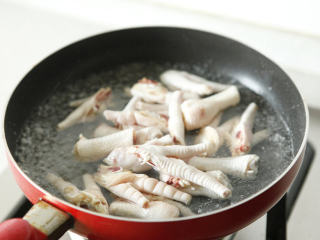 2、酱凤爪 ,适量清水烧开，倒入料酒、姜片，将鸡爪焯水后捞出。