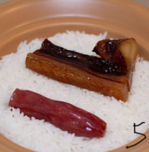5、腊味煲仔饭,饭煮开后把腊味整个的放入,尽量不要切开,这样味道会一直保存在里边,然后盖盖儿,最小火闷吧,大约十五分钟差不多