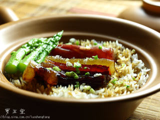 7、腊味煲仔饭,时间到了后赶紧放入加了老抽的鱼汁,加完汁后再焖个三分钟左右把豉香味焖出来就差不多了,然后把腊味取出来切片和露笋摆在饭上,撒小葱花,然后你可以低头闻一下味道,不喜欢你找我来.