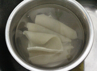 4、泡椒猪皮,煮好的猪皮捞出，用凉水反复冲洗到水变得很清为好，然后切成细条