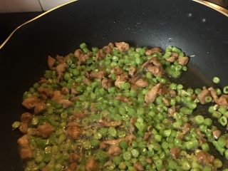 9、豆角猪肉炒鸡蛋,加入己豆角粒翻炒均匀,然后加入适量的盐和水。