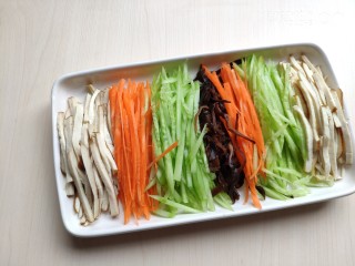11、香干拌三丝,将切好的香干丝、黄瓜丝、胡萝卜和木耳丝摆放到盘中。