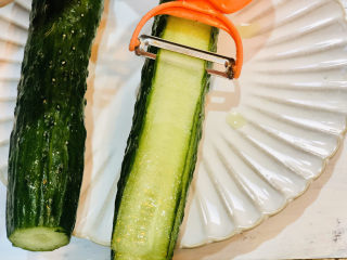 2、凉拌黄瓜卷,用刮皮刀将黄瓜刮成片状；