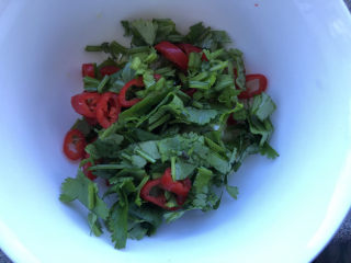 11、尖椒皮蛋,先把蒜、葱、香菜和尖椒放在碗里。