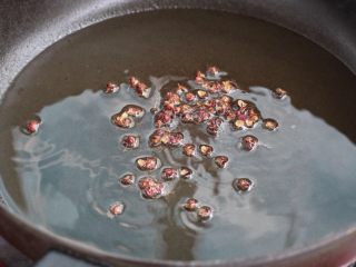 7、黄瓜拌腐竹,再次加热刚才炸花生米的油锅，放入花椒粒小火炒出香味，将花椒粒捞出丢弃不用。