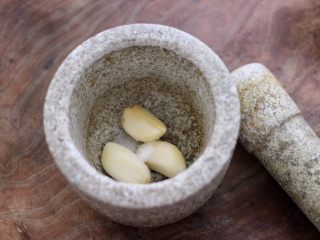 9、温拌海螺,大蒜去皮后,用工具把蒜捣成蒜泥。