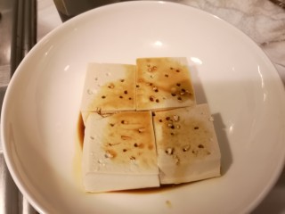 3、肉片豆花/不辣版,放入盘中。用筷子戳几个洞加入少许生抽。