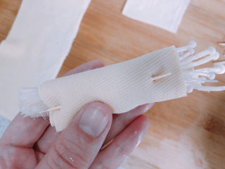 7、豆皮金针菇卷,卷到最后的时候用牙签串起来。