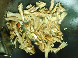 4、手撕咸鱼,锅中入油下姜、蒜和泡酒椒煸出味后入咸鱼煸至两面金黄推一边用底油把青椒段编炒小会再一同翻炒‘加入泡辣椒的酒和些许生抽翻炒