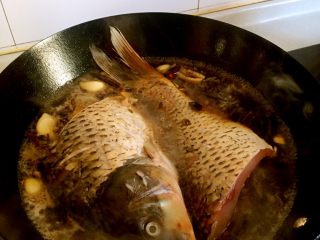 5、家常炖鱼,放入鲤鱼，加水淹没鲤鱼一半即可，大火煮开，改中小火慢炖，避免糊锅，不时翻动