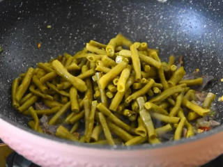 5、麻辣酸脆,又下饭又下酒,尝上一口就停不下来,倒入酸豆角继续翻炒。