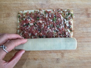 6、糖醋东北肉签子,将豆腐皮沿一边卷起，尽量卷得紧一些。