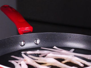 5、往鸡爪里倒入一瓶啤酒，吃起来大呼过瘾,将鸡爪放在锅中，水的量没过鸡爪即可，加入2勺的料酒给鸡爪焯水，这样可以去除鸡爪的腥味。