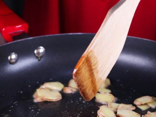 8、往鸡爪里倒入一瓶啤酒，吃起来大呼过瘾,锅烧热，加入适量的油，将冰糖下锅炒至融化后，放入生姜片一同炒香后。