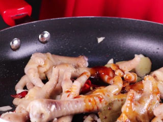 9、往鸡爪里倒入一瓶啤酒，吃起来大呼过瘾,接着将鸡爪下锅一同翻炒，加入八角、干辣椒、香叶、蒜末炒香，倒入1大勺的耗油、一大勺的生抽，一大勺的老抽、一小勺盐、一小勺白砂糖一同翻炒均匀。