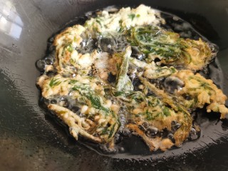 12、炸香椿鱼,用筷子翻动香椿,炸制金黄酥脆时捞出控油。