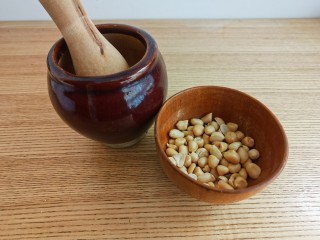 6、菠菜拌花生米,烤好的花生米晾凉后去掉花生皮。取一半的花生米放入蒜臼中捣碎。