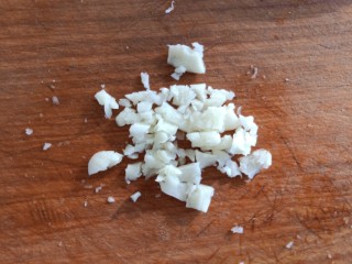 9、凉拌腐竹黄瓜,现在我们来做调料汁。剥两瓣大蒜，将大蒜拍碎切成蒜蓉。