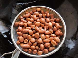 5、香酥油炸花生米,仔细看的话，花生米的外皮颜色和生花生米已经不一样了，稍微有些变暗了，并且密集的噼啪声已经消失，个别的花生米外衣也炸裂了，这个时候就可以捞出来控油了。花生捞出来之后的余热也会继续加热花生，所以如果等到花生米明显变色再捞的话就意味着炸过头了。