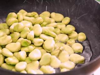 3、无比鲜美的葱油蚕豆,又香又嫩软绵绵,将蚕豆倒入锅中，炒匀