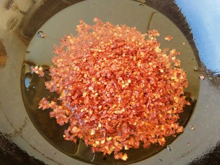 14、#辣味#秘制喷香油辣子,等油温5成热时，我们倒入辣椒面