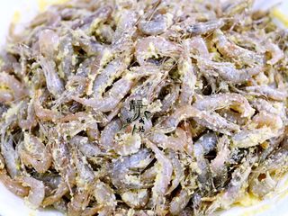 4、独家韭菜炒河虾,下手,充分拌匀,让小河虾均匀地周身沾上一层薄薄的玉米面。