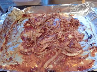 11、洛氏新煮义--烧烤黑椒猪肉VS烧烤孜然鱿鱼,然后锡箔纸上刷食用油，放入鱿鱼，我是连酱汁一起倒进去的，这是烤了10分钟的样子，依旧200度