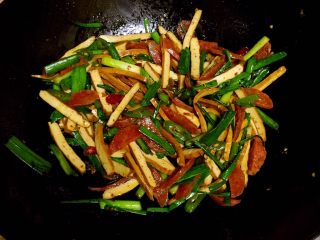 10、腊肠炒香干,出锅前放入青蒜叶炒至断生即可装盘。