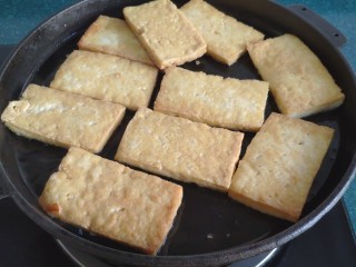 12、铁板豆腐,等到豆腐一面煎黄后，给它翻个儿面继续煎。