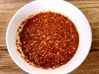 4、麻辣金针菇,锅里烧热油，关火静置二十秒，再浇到辣椒粉里，（为什么要静置二十秒呢，因为辣椒粉遇高温容易焦，静置一下，等热油温度不会那么高的时候再把油倒到辣椒粉里，这样做出来的辣椒油颜色鲜亮，香味浓郁）自制辣椒油就做好了