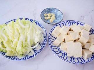 2、白菜豆腐,白菜洗净切成条状，豆腐切成小块，我切的是正方形的，方便后面炒不易断，蒜切片