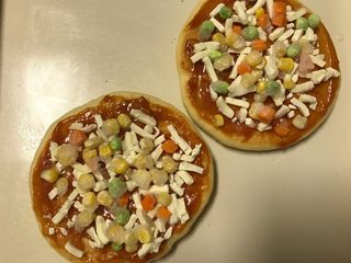 9、迷你香肠披萨,撒上适量的马苏里拉芝士再放一层蔬菜粒。