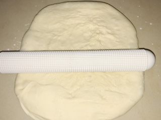 11、葱香芝士香肠面包,桌面上撒少许面粉，将面团移上去，光滑面朝下，湿粘面朝上，撒少许面粉，擀开。