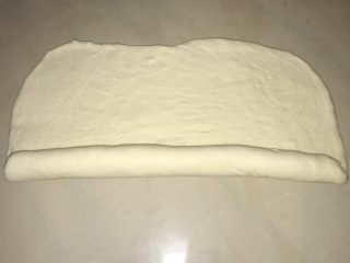 13、葱香芝士香肠面包,将面团从一侧卷起。