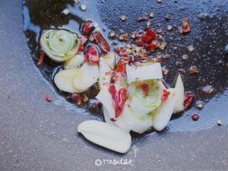 4、青椒炒豆干,锅烧热倒入适量的油，放入花椒，蒜瓣和红辣椒、葱段爆香。