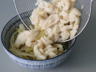 9、水煮鱼片,将焯烫熟的巴沙鱼捞出放入铺好豆芽的碗中。